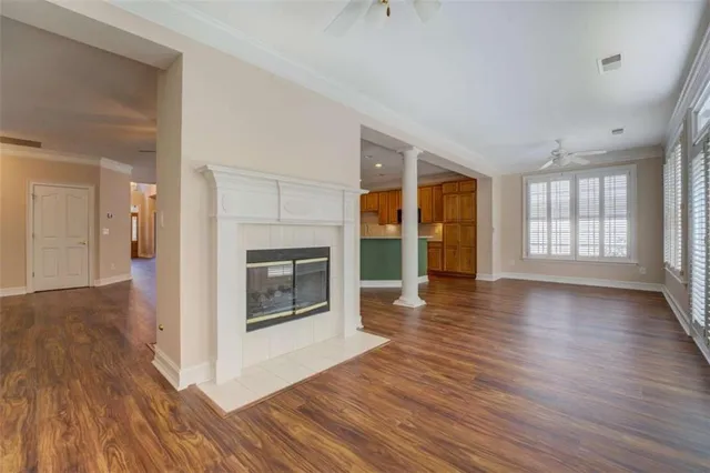 an empty room with wooden floor fireplace and windows