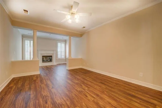 an empty room with wooden floor fireplace and windows