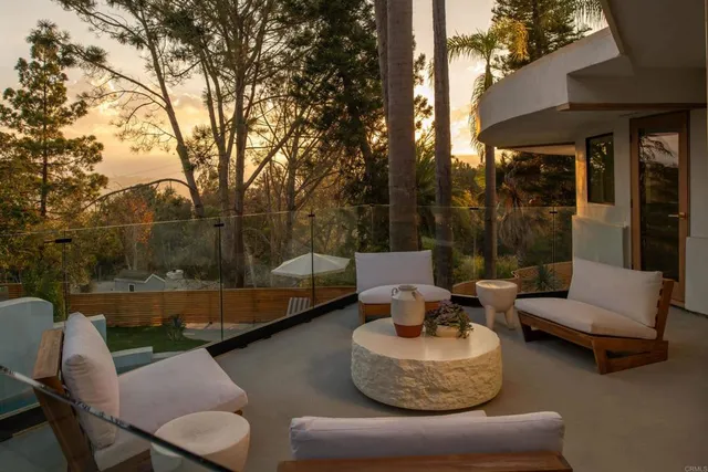 a balcony with couches and a potted plant on a table
