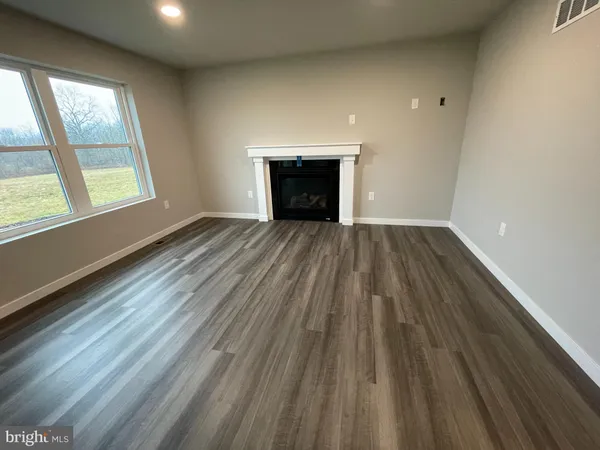 an empty room with wooden floor fireplace and windows