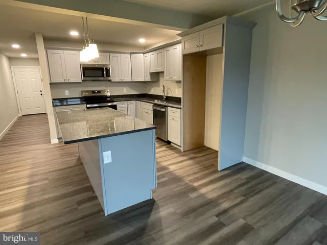 a kitchen with kitchen island wooden floors appliances and cabinets