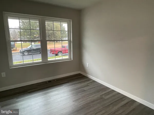 a view of an empty room with wooden floor and windows