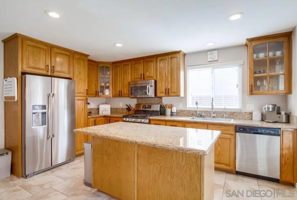 9118 Gotta Place Lakeside, CA 92040 - Photo 11 of 50 a kitchen with stainless steel appliances granite countertop a refrigerator a sink a stove a dining table and chairs