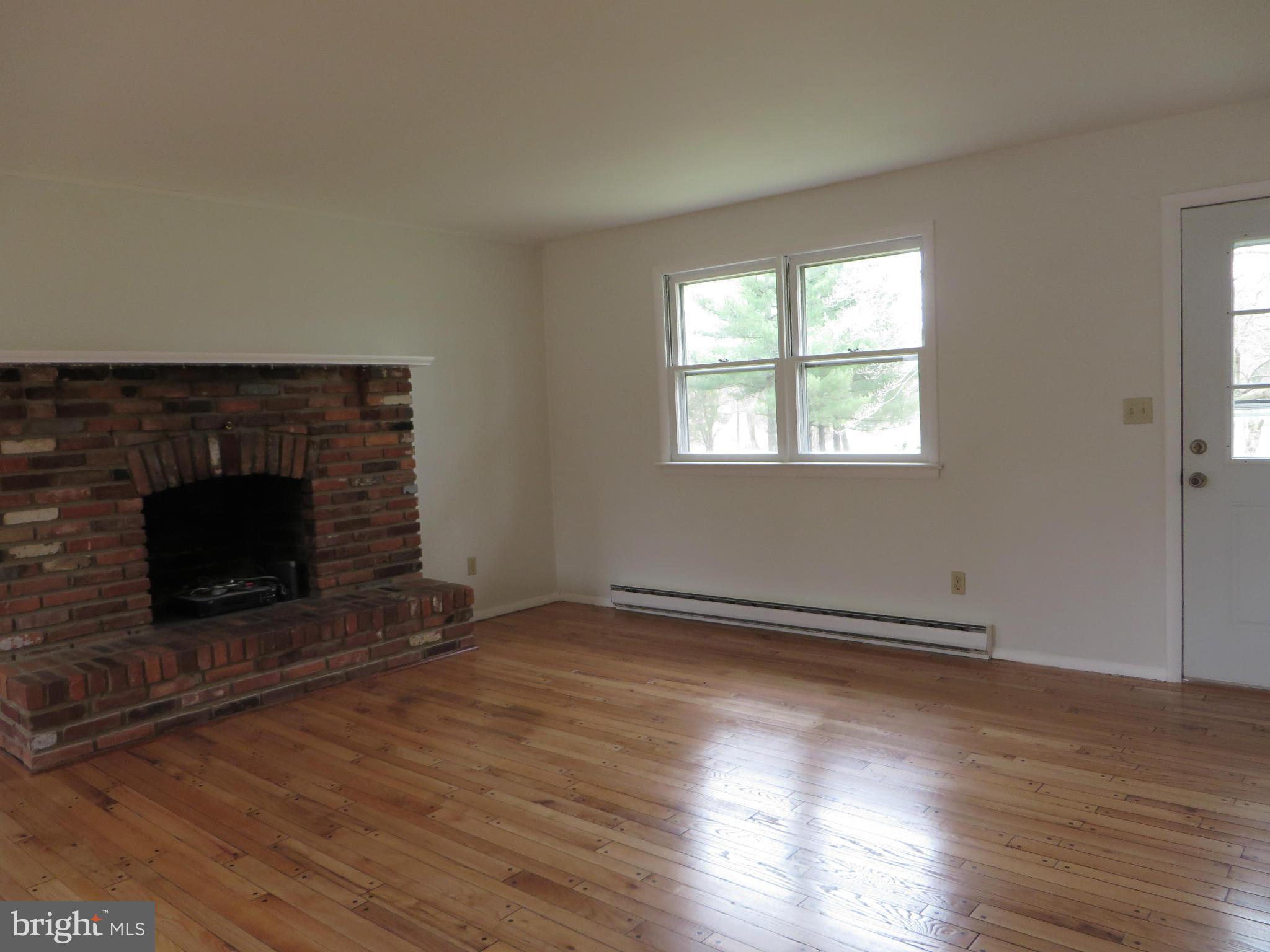4101 Baptist Road Taneytown, MD 21787 - Photo 8 of 30 an empty room with wooden floor fireplace and windows
