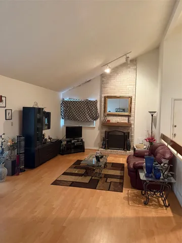 a living room with furniture a flat screen tv and a refrigerator