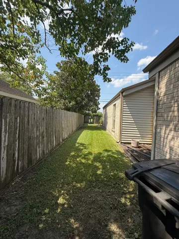 a view of backyard with wooden fence and large trees