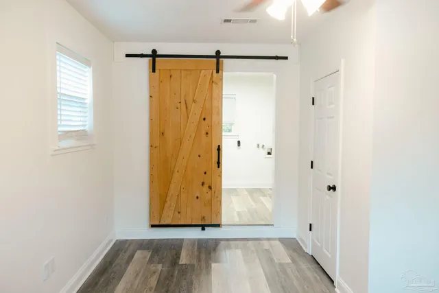 a view of an empty room with wooden floor and a window