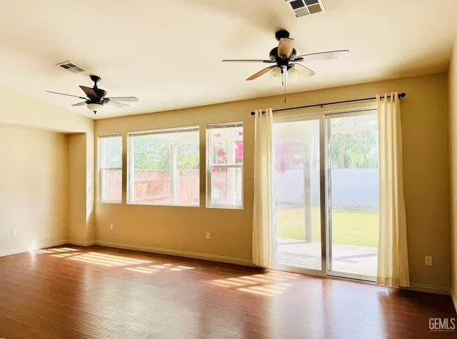 a view of an empty room with a window and wooden floor