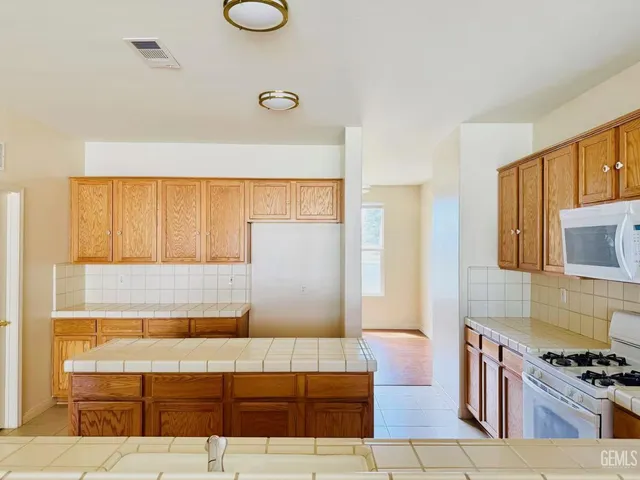 a living room with stainless steel appliances kitchen island granite countertop a rug and a window