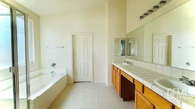 a bathroom with a granite countertop tub sink and mirror