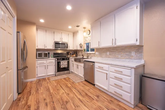 a kitchen with granite countertop a sink stainless steel appliances and cabinets