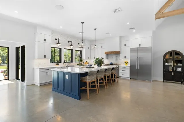 a kitchen with stainless steel appliances kitchen island granite countertop a refrigerator and a sink
