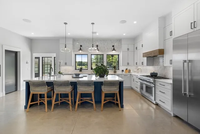 a kitchen with kitchen island a dining table chairs stainless steel appliances and cabinets