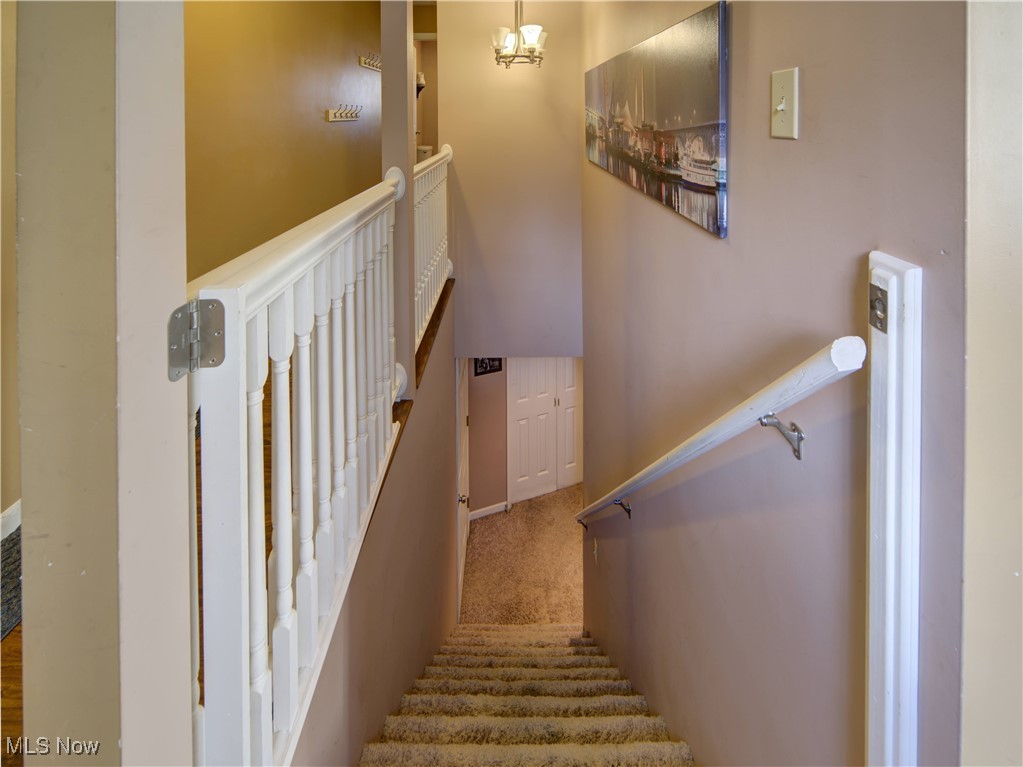 17161 Burrows Road Thompson, OH 44086 - Photo 25 of 48 Stairs with carpet floors and a notable chandelier