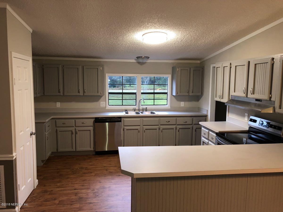 54254 Heller Road Callahan, FL 32011 - Photo 6 of 25 a kitchen with kitchen island granite countertop a sink cabinets and wooden floor
