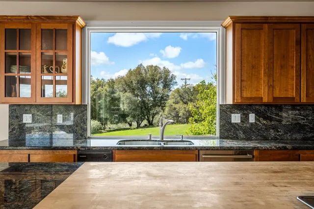 a kitchen with granite countertop a sink a stove and cabinets