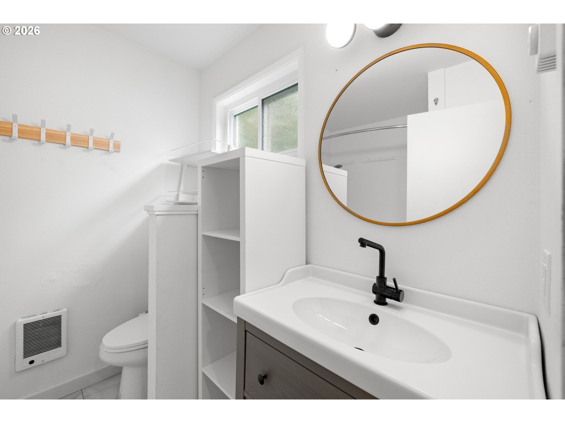 4594 Southwest Caldew Street, Unit A Portland, OR 97219 - Photo 21 of 29 a bathroom with a sink a mirror a toilet and a window