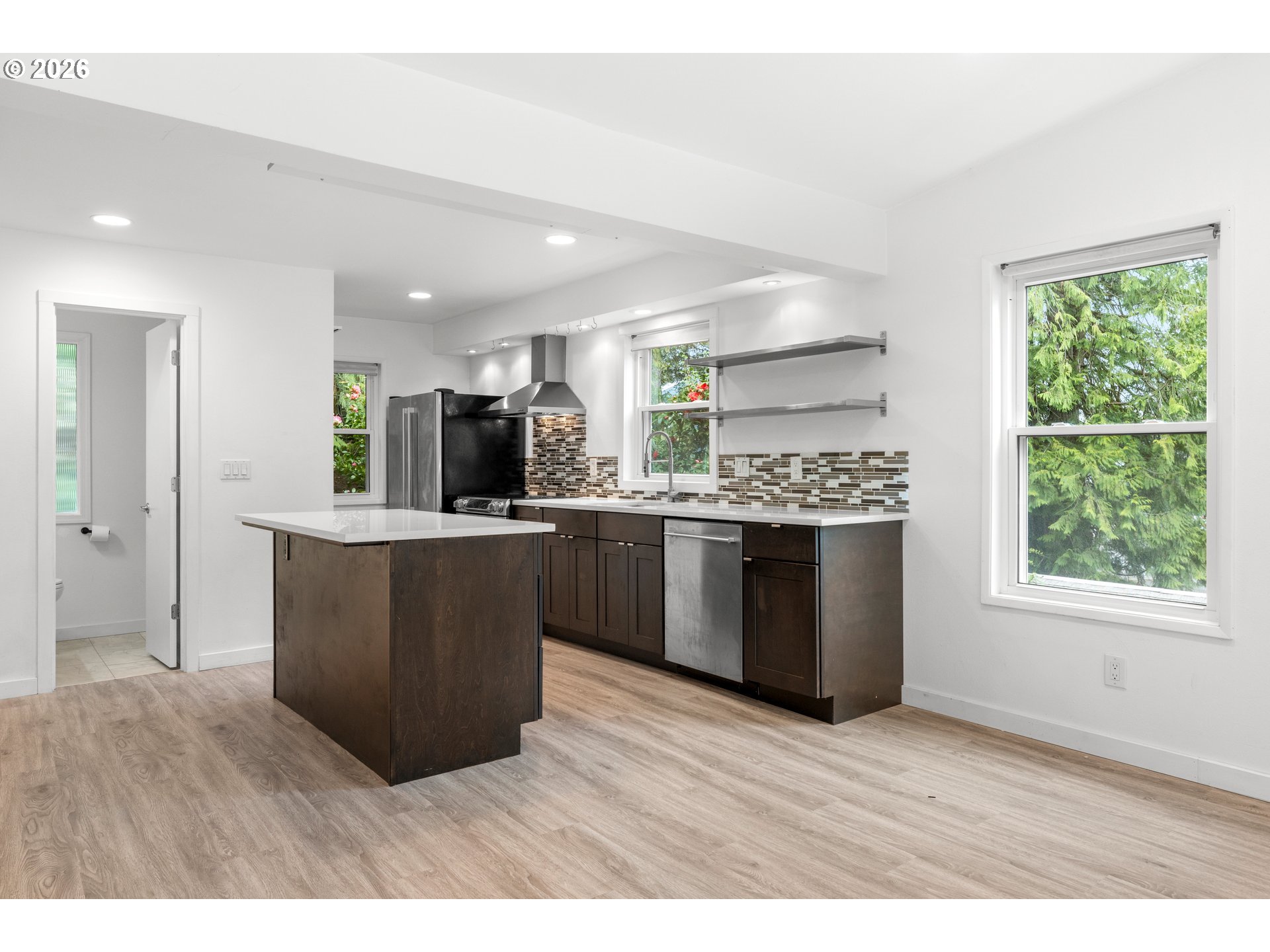 4594 Southwest Caldew Street, Unit A Portland, OR 97219 - Photo 5 of 29 a kitchen with stainless steel appliances kitchen island wooden cabinets and granite counter tops