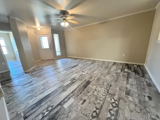 a view of an empty room with window and wooden floor