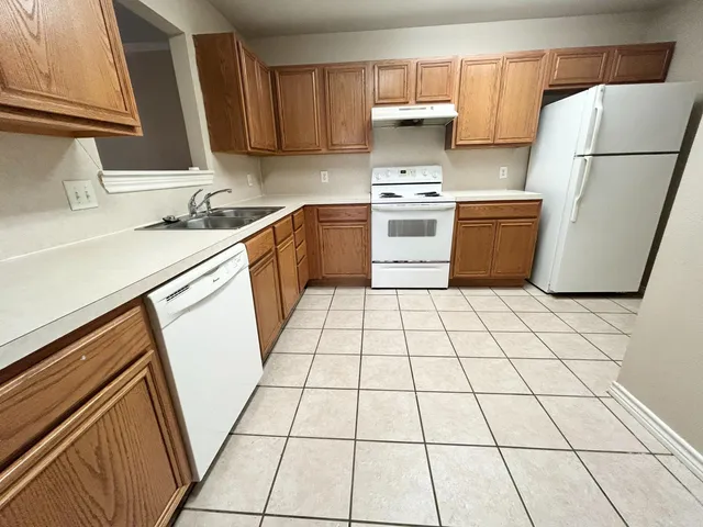 a kitchen with a sink a stove top oven and white cabinets