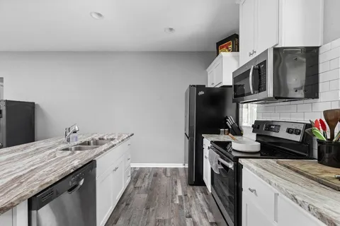 a kitchen with appliances a sink cabinets and wooden floor