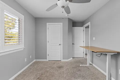 a view of a bedroom with wooden floor and a ceiling fan