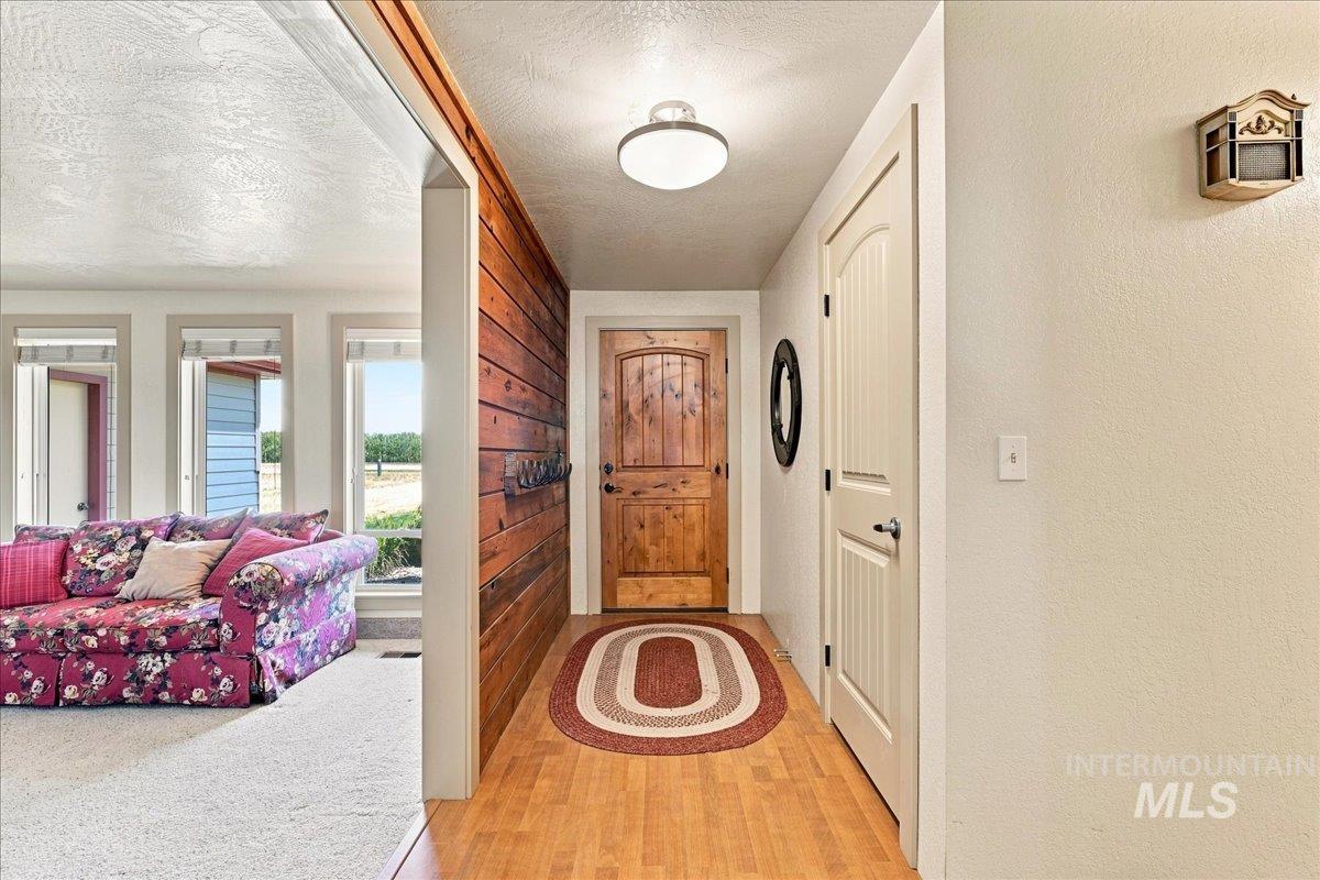 26201 Hop Road Caldwell, ID 83607 - Photo 5 of 45 Entryway featuring wood-finish flooring and a wood-paneled accent wall