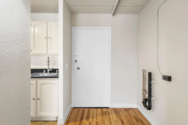 a view of an empty room with a window and wooden floor