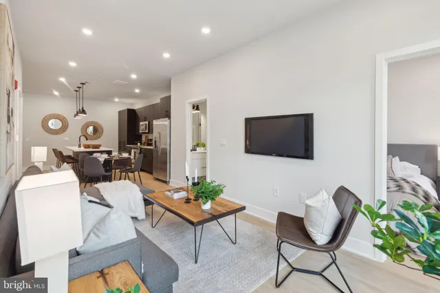 a living room with furniture a flat screen tv and kitchen view