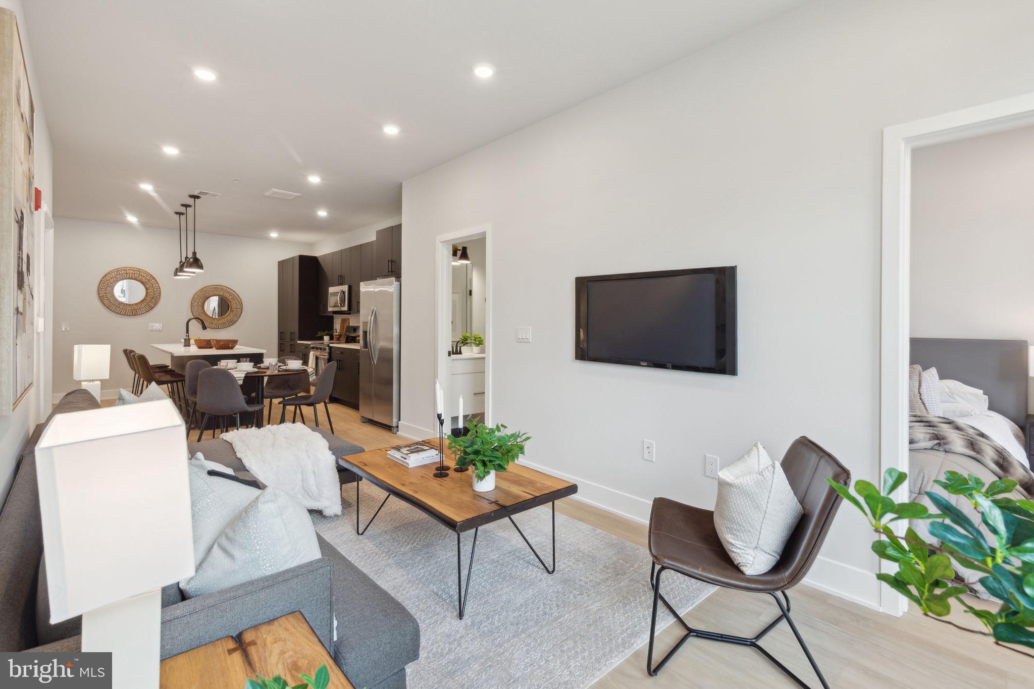 6910 Ridge Avenue, Unit 220 Philadelphia, PA 19128 - Photo 12 of 25 a living room with furniture a flat screen tv and kitchen view