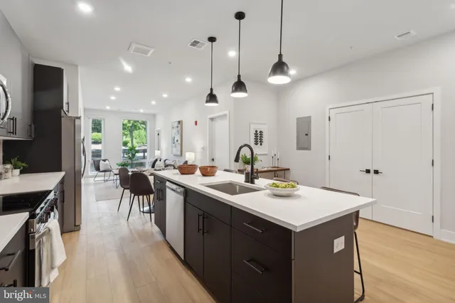 a kitchen with a sink a counter space appliances and wooden floor