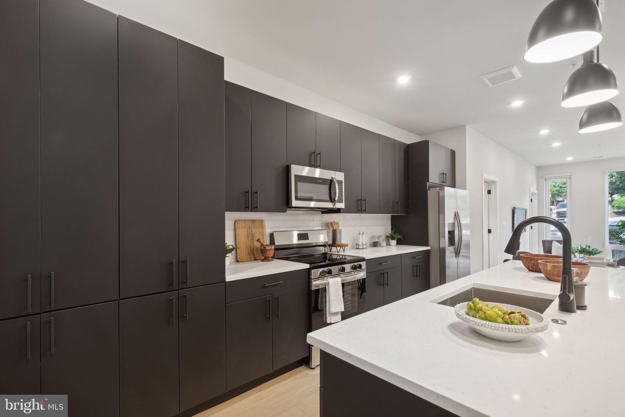 6910 Ridge Avenue, Unit 220 Philadelphia, PA 19128 - Photo 5 of 25 a kitchen with a sink a stove and chairs