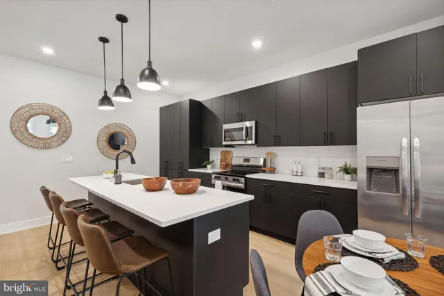 a kitchen with a refrigerator a sink a stove and chairs with wooden floor