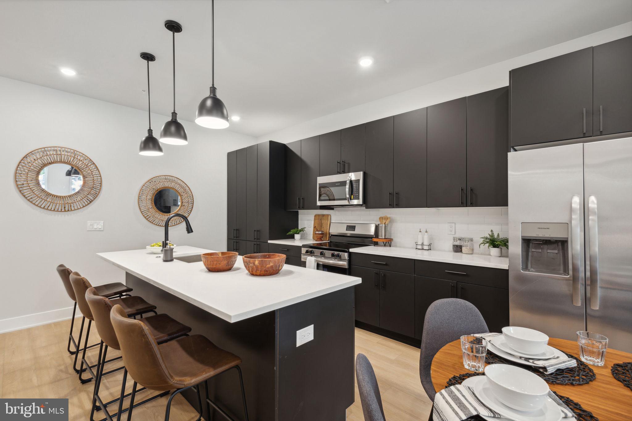 6910 Ridge Avenue, Unit 220 Philadelphia, PA 19128 - Photo 6 of 25 a kitchen with a refrigerator a sink a stove and chairs with wooden floor