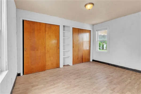 a view of an empty room with window and closet area