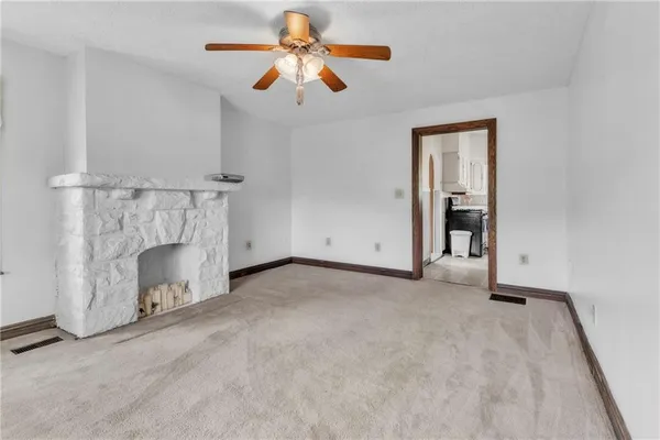 an empty room with a fireplace and a ceiling fan