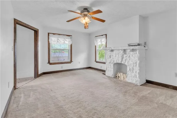 an empty room with windows and fireplace