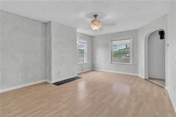 an empty room with windows and chandelier fan