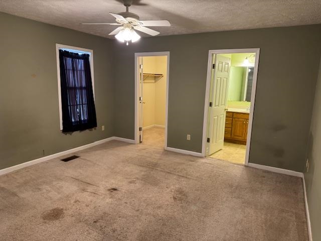 840 Butler Street Bolivar, TN 38008 - Photo 8 of 16 Unfurnished bedroom featuring light carpet, a textured ceiling, a walk in closet, ceiling fan, and connected bathroom