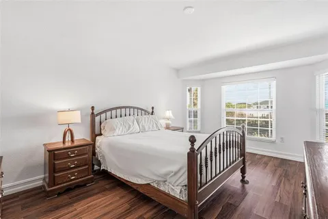 a bedroom with a bed and a large window with wooden floor