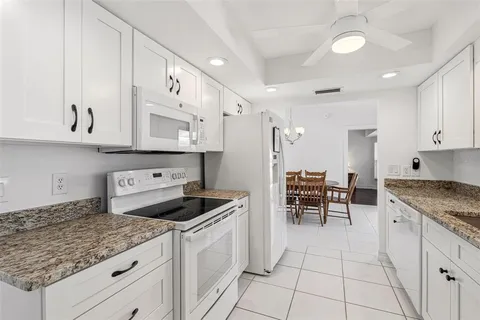 a kitchen with granite countertop a sink a stove and cabinets