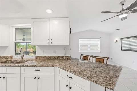 a kitchen with granite countertop a sink white cabinets and a window