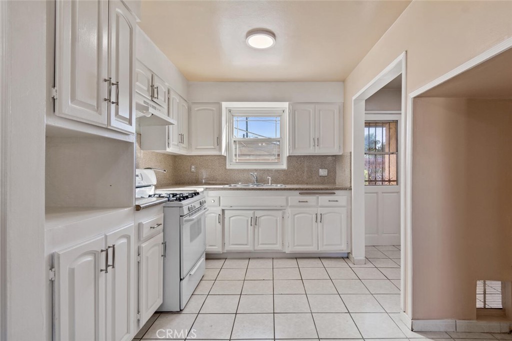 13438 Mercer Street Pacoima, CA 91331 - Photo 11 of 39 a kitchen with stainless steel appliances granite countertop a sink and dishwasher a refrigerator with white cabinets