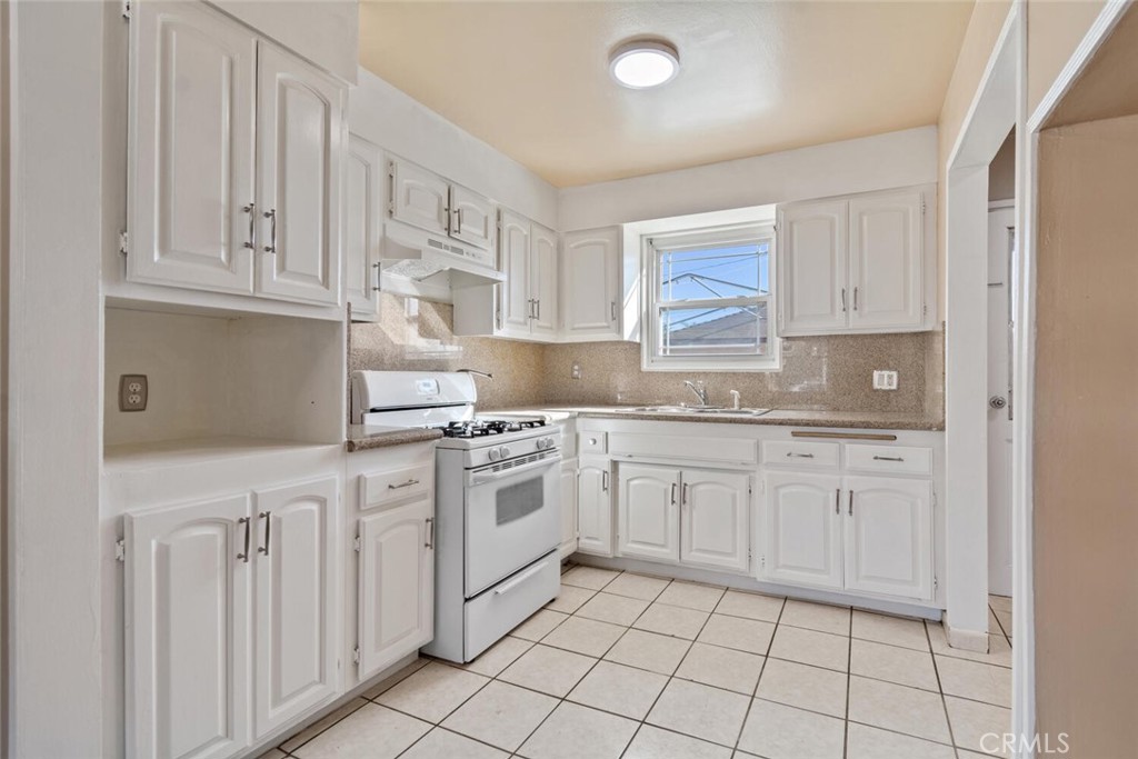 13438 Mercer Street Pacoima, CA 91331 - Photo 10 of 39 a kitchen with granite countertop white cabinets and white appliances