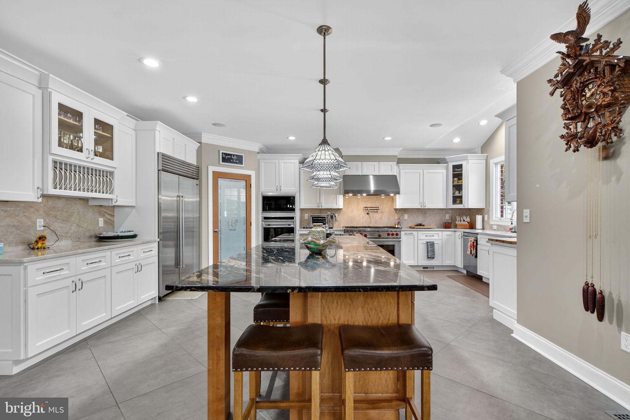 7484 Wilson Road Warrenton, VA 20186 - Photo 60 of 81 a large kitchen with kitchen island granite countertop a stove a sink a refrigerator and white cabinets with wooden floor