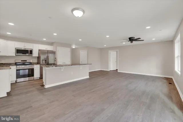 a view of kitchen with kitchen island granite countertop a stove top oven a sink and dishwasher with wooden floor