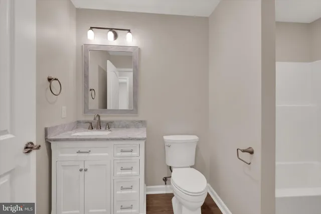 a bathroom with a granite countertop toilet sink and mirror