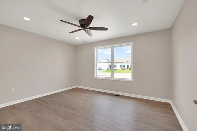 an empty room with wooden floor fan and windows