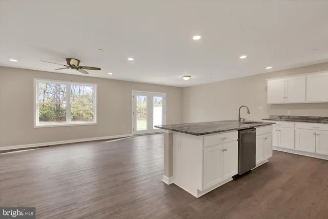 a kitchen with granite countertop white cabinets and wooden floors