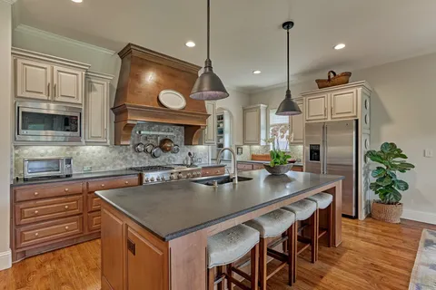 a kitchen with stainless steel appliances granite countertop a stove a sink and a wooden cabinets